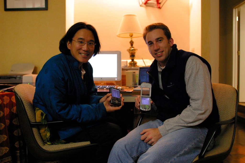 Holding up old Palm and Handspring devices in Cupertino on January 23, 2003. The one Alex is displaying is actually a phone! 